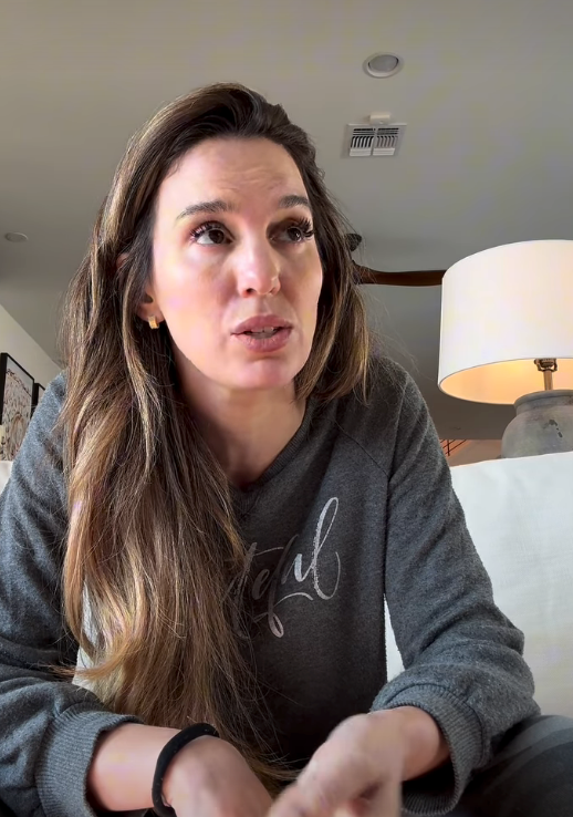 Person som sitter innendørs, iført en uformell topp, snakker med et gjennomtenkt uttrykk