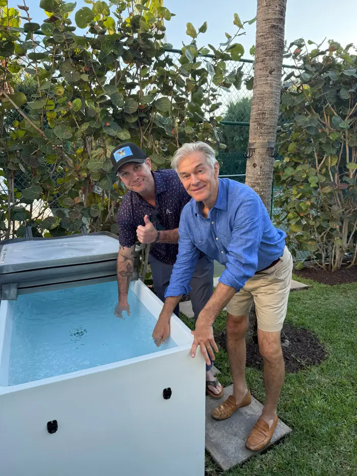 To menn ved et utendørs isbad; man gir tommel opp. Begge er uformelt kledd i shorts og skjorte