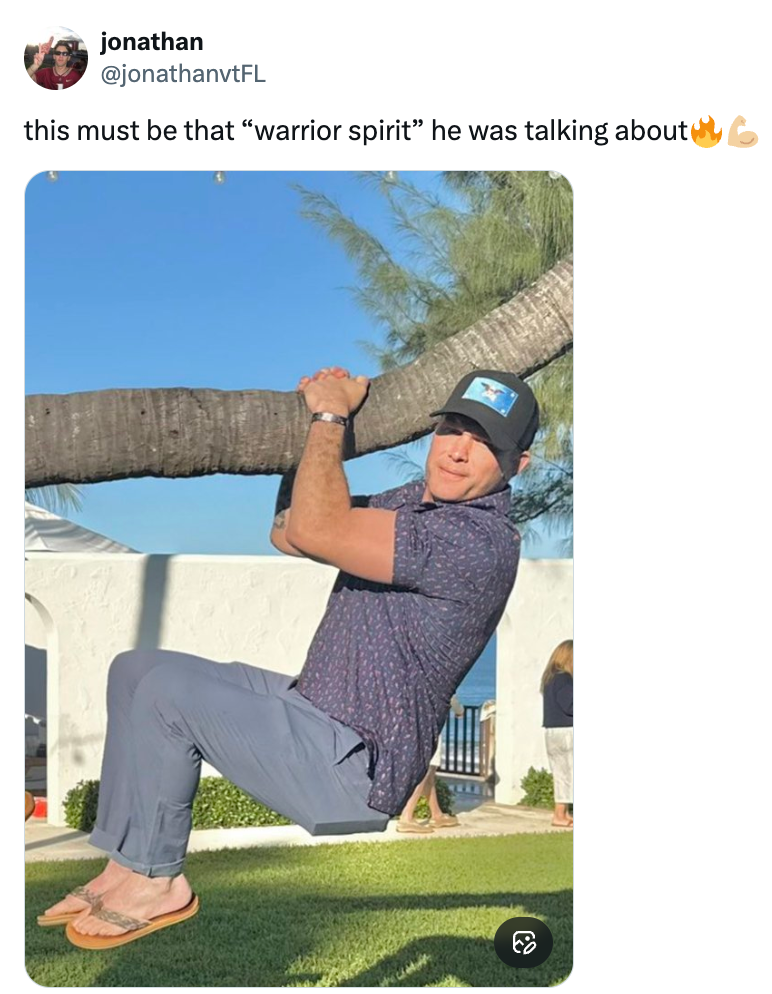 En mann iført caps og fritidsklær henger lekent fra en tregren