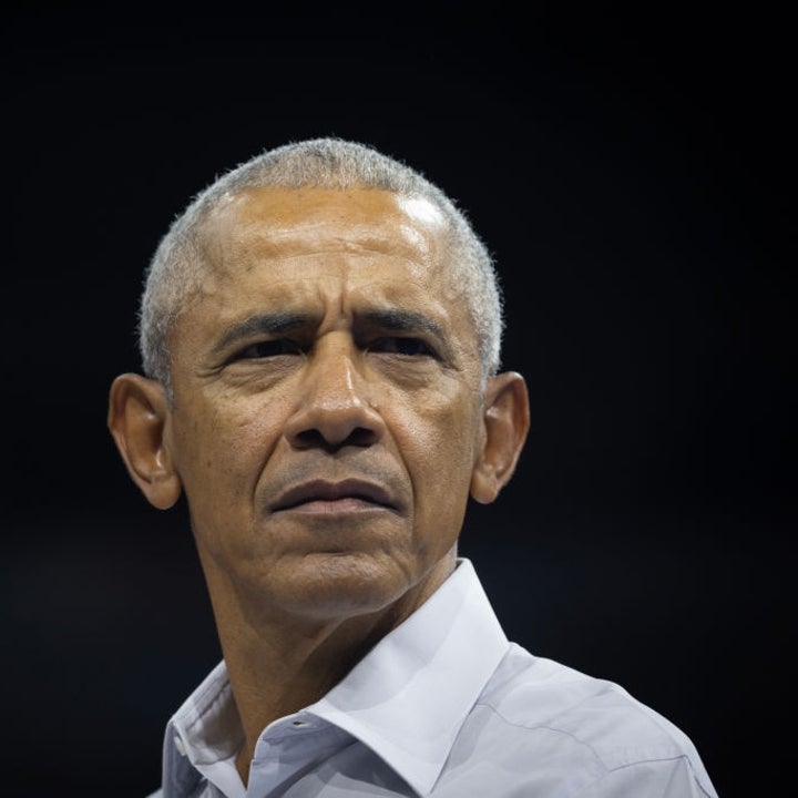 En person i en hvit skjorte ser ettertenksomt i det fjerne, fanget mot en mørk bakgrunn