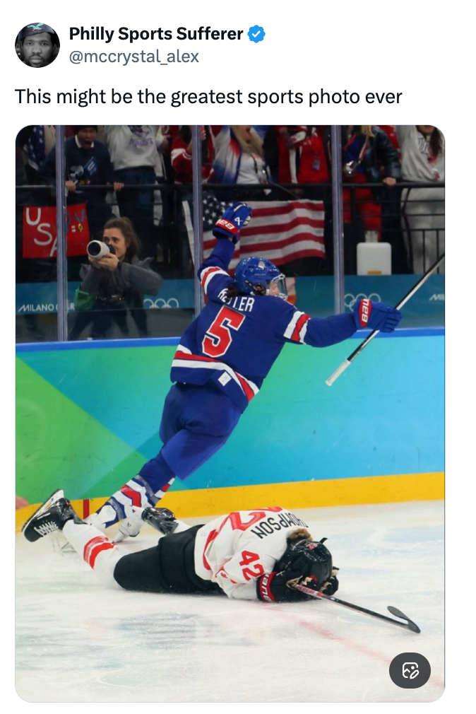 En hockeyspiller feirer mens en annen ligger på isen under en kamp, ​​med publikum som jubler i bakgrunnen