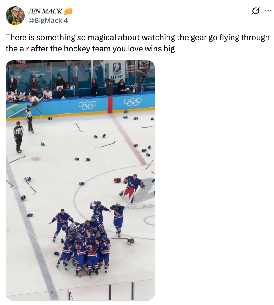 Hockeylaget feirer på is mens utstyret er spredt rundt. Tilskuere ser på fra tribunen under et olympisk arrangement