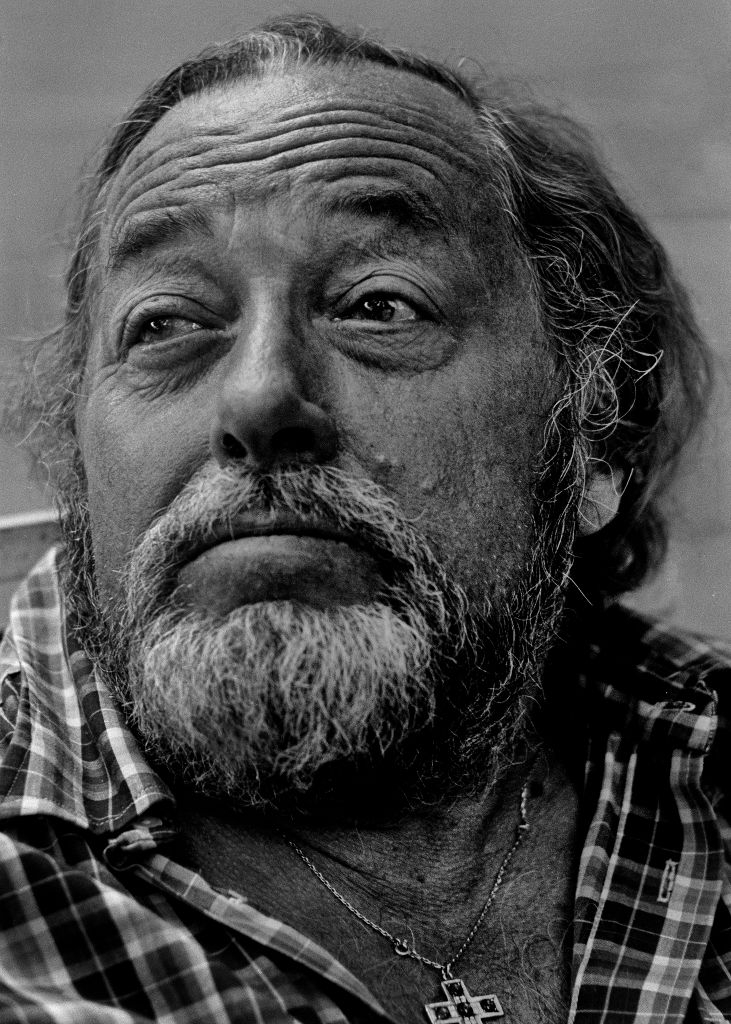 Mann med skjegg og rutete skjorte ser ettertenksomt til siden