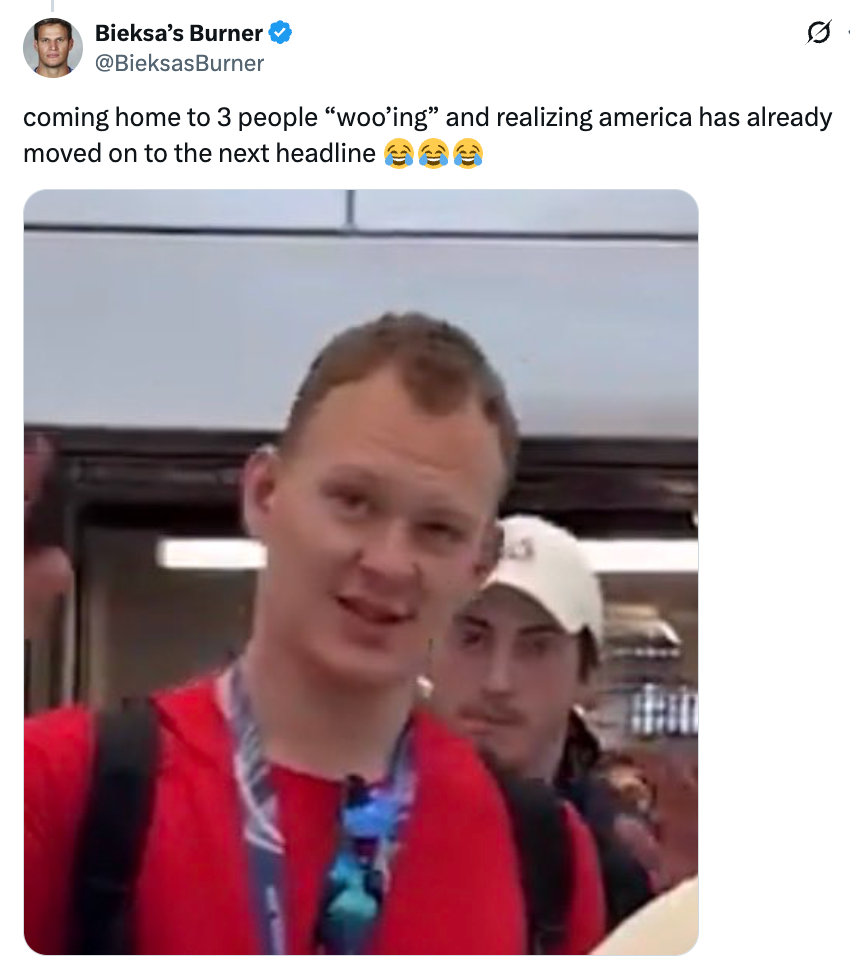 En mann i rød skjorte smiler mens en annen person står bak ham i en innendørs setting. Bildetekst: "kommer hjem til 3 personer 'beiler'..."