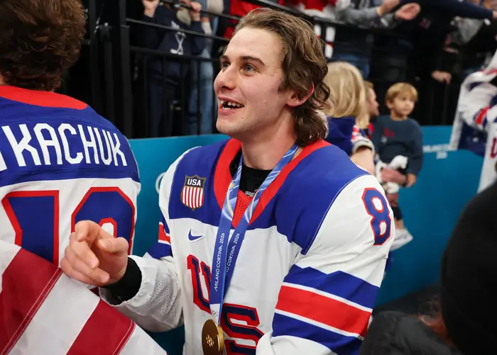 Hockeyspiller iført en USA-trøye med en medalje rundt halsen, smiler og samhandler med fans på et arrangement
