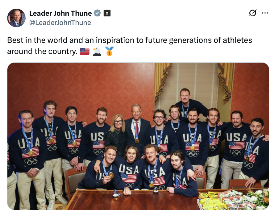 Gruppe av olympiske idrettsutøvere i USA gensere poserer med et par i formell antrekk. Medaljer henger rundt flere idrettsutøvere' halser