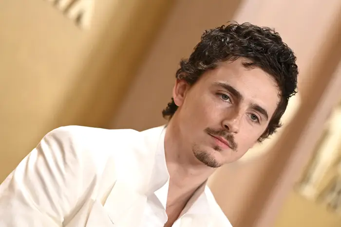 En person i hvit dress poserer ved en formell begivenhet, og ser litt til siden