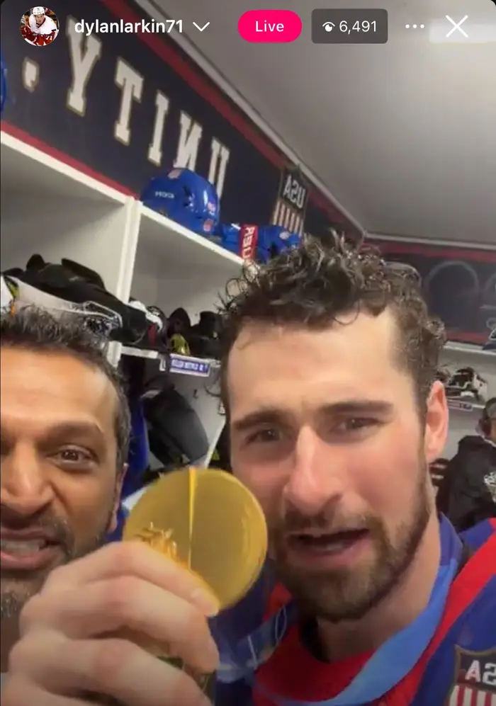 Hockeyspiller og fan i garderoben feirer; spiller holder opp en gullmedalje med spenning