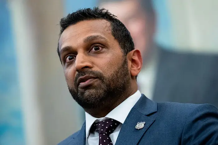 En person i dress og slips er i fokus, eventuelt ved en formell begivenhet eller setting. Bakgrunnselementer er uskarpe