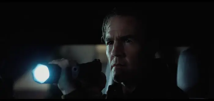 Person i mørke omgivelser holder en lommelykt, virker fokusert og intens, noe som antyder en spennende eller dramatisk scene fra et TV-program eller en film