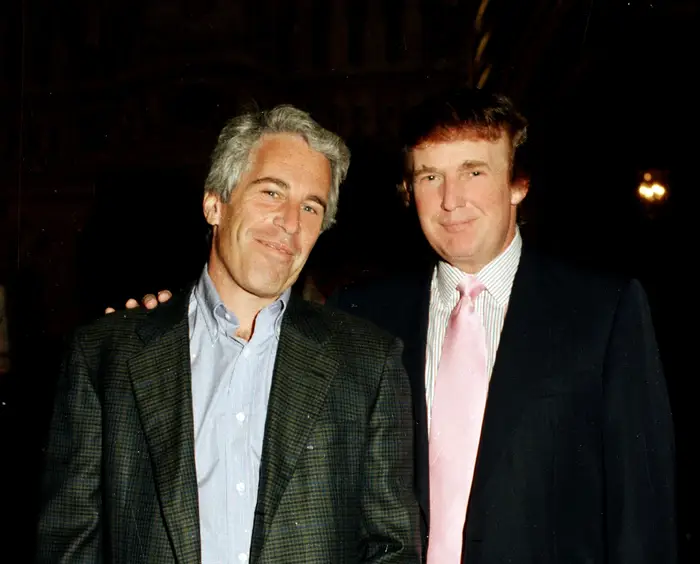 To menn poserer for et bilde, den ene i blazer og jeans, den andre i dress med rosa slips