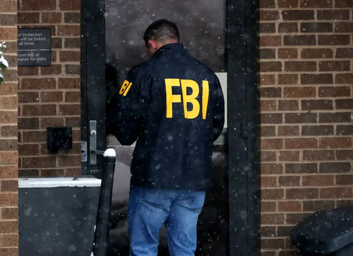 FBI-agent i jakke står ved inngangen til en snødekt bygning og ser ut til å gå inn eller undersøke