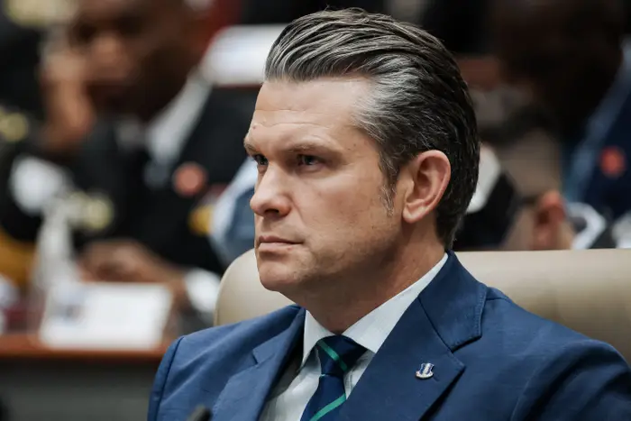 Pete Hegseth i dress sitter oppmerksomt i et konferansemiljø, og virker fokusert og engasjert i saksbehandlingen