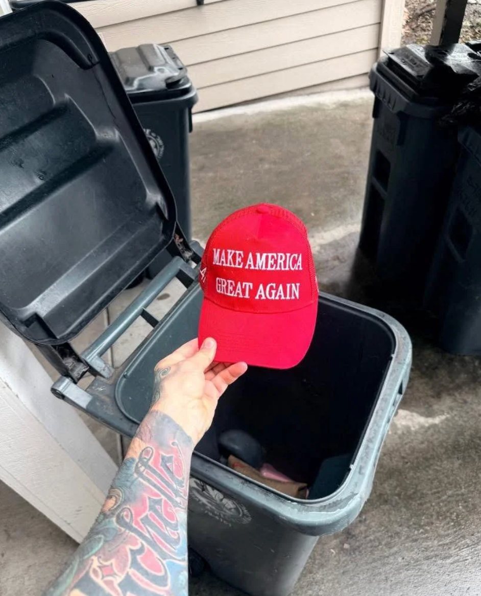 En person som holder en "Make America Great Again" cap, i ferd med å kaste den i en søppelbøtte