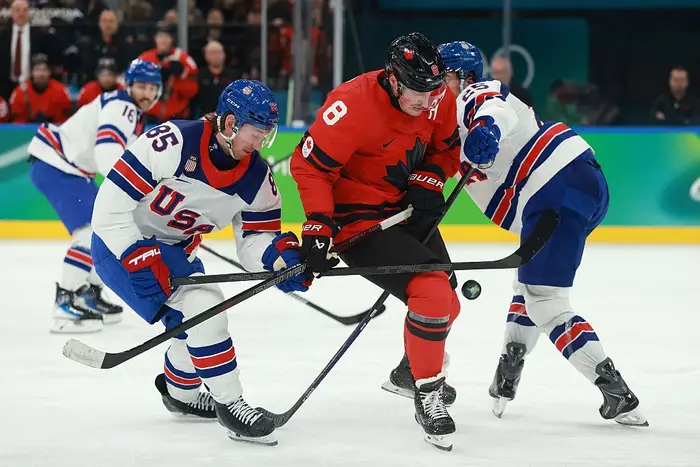 Hockeyspillere fra Canada og USA konkurrerer om pucken under en kamp