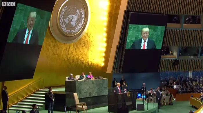 Verdensleder taler ved talerstolen i FNs generalforsamling, stort emblem over. Publikum og funksjonærer synlig i en romslig sal