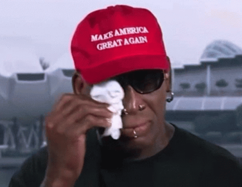 Person som har på seg en "Make America Great Again" luen tørker en tåre med et papirserviett, iført solbriller og nesesmykker