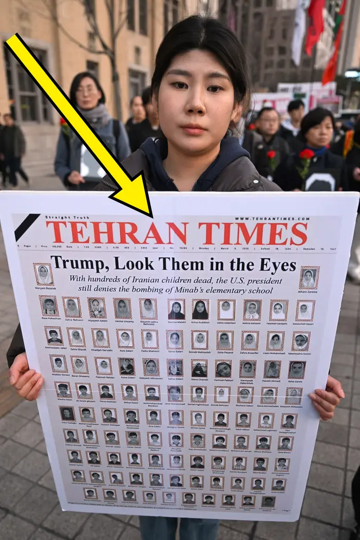 Person som holder en plakat som ligner en Teheran Times-forside, som fremhever virkningen av bombingen av Minabs barneskole