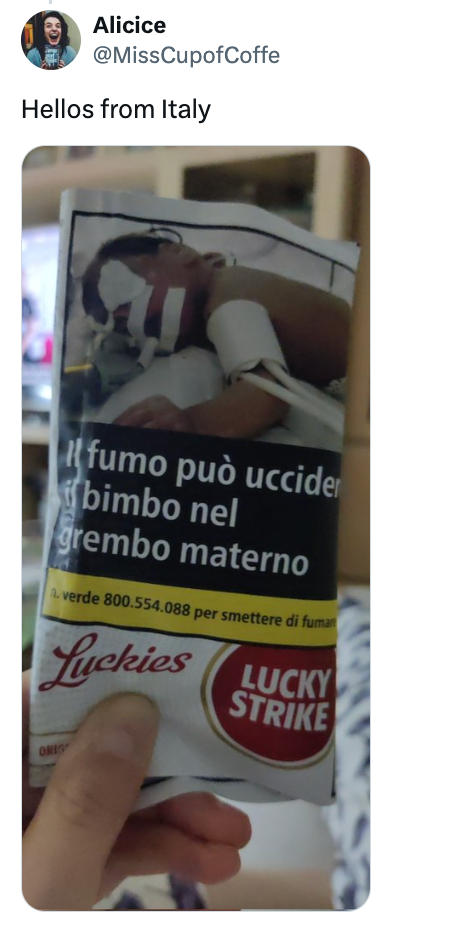 Person som holder en sigarettpakke med advarsel mot røyking på italiensk, og viser et bilde av en baby i en kuvøse