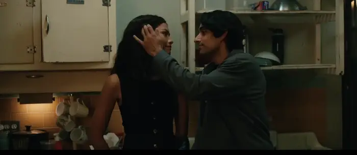 En mann tar forsiktig på en kvinnes ansikt i et koselig kjøkken, og formidler intimitet og varme