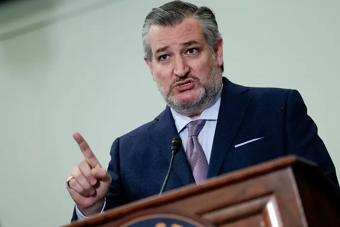 En mann i dress og slips snakker lidenskapelig ved et podium og gestikulerer med hånden for å understreke