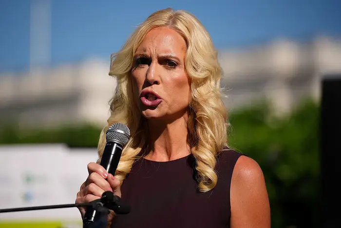 Person med krøllet hår snakker inn i en mikrofon på et utendørsarrangement