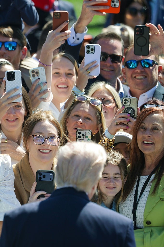 Publikum tar bilder med telefoner mens de smiler foran en mann. Ansiktene er entusiastiske og fokuserte på motivet