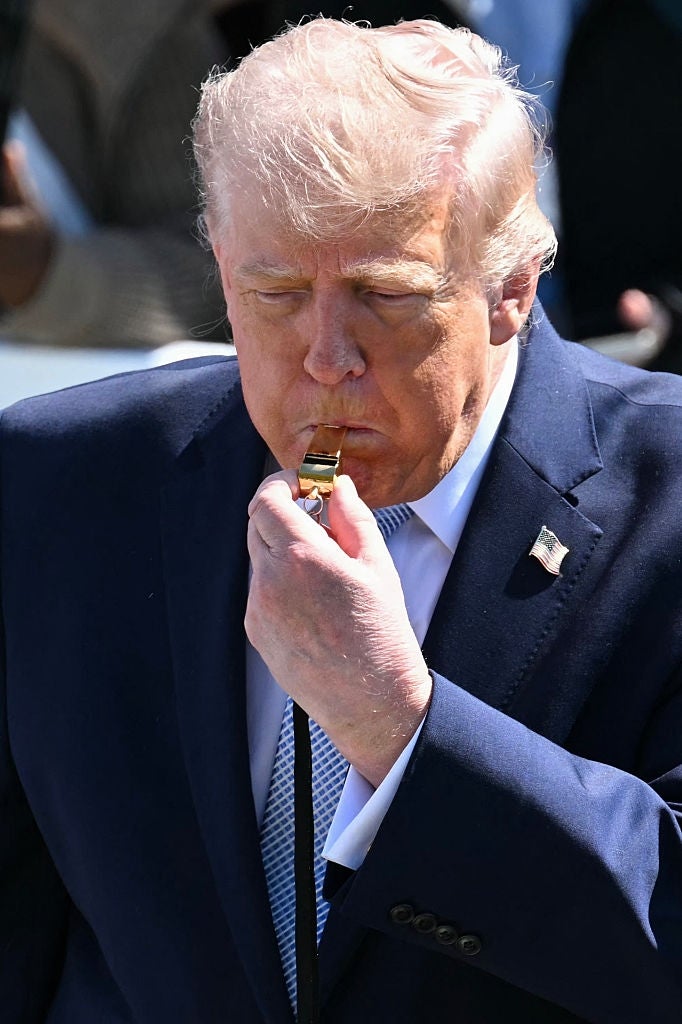 Person som har på seg en dress, står utendørs, blåser i en fløyte