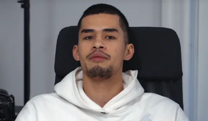 Person som sitter i en stol, iført en hettegenser, ser direkte på kameraet