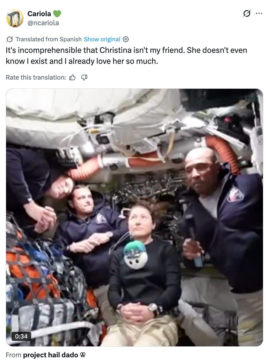 Gruppe astronauter inne i et romfartøy med en som holder en dukke. Det er relatert til prosjektet "Hail Dado."