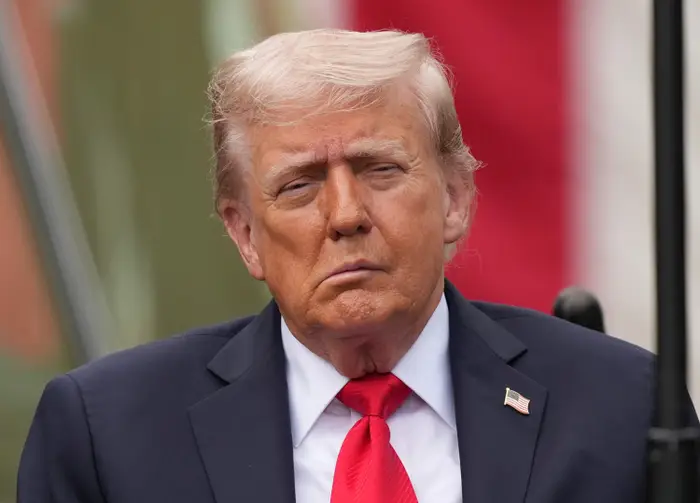 En person i dress og rødt slips deltar på et utendørsarrangement og virker fokusert