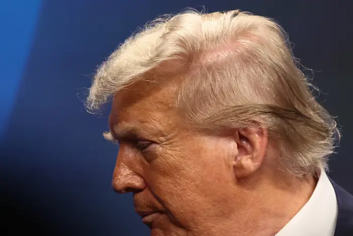 Donald Trump med tilbaketrukket hår vises i profil mot en nøytral bakgrunn, og ser nedover