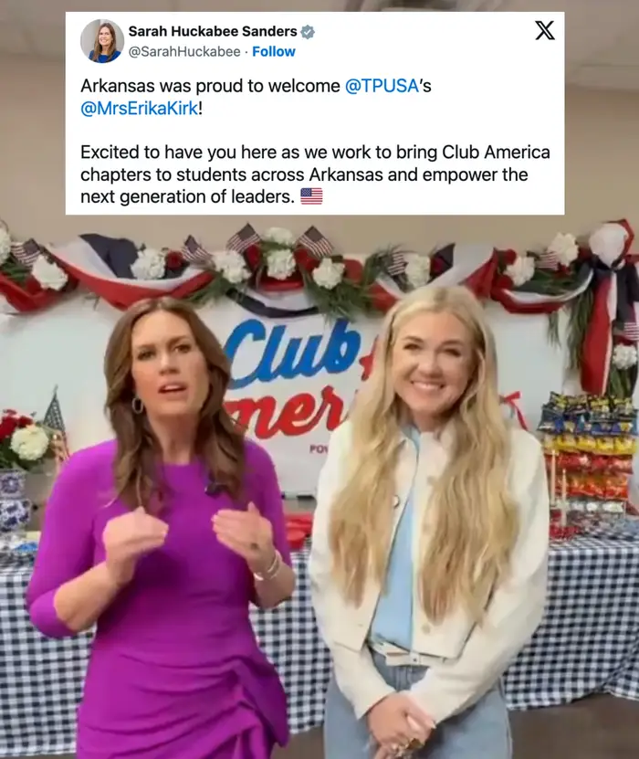 To kvinner står foran et bord med snacks og patriotiske dekorasjoner. Den ene har på seg en lilla kjole, den andre en hvit skjorte og beige jakke