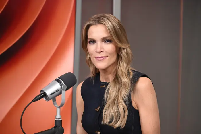 Person med langt hår, iført en ermeløs svart topp, sitter ved en mikrofon i studiomiljø