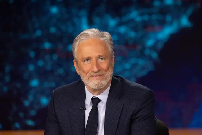 Eldre mann med skjegg, iført dress og slips, smilende i studio