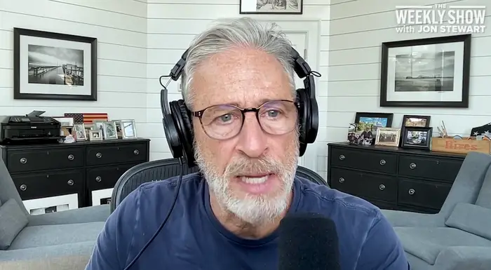 Mann med briller og hodetelefoner snakker inn i en mikrofon på et hjemmekontor