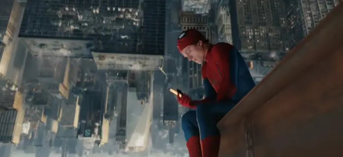 Spider-Man i kostyme, sittende på kanten av en bygning, ved hjelp av en smarttelefon, med et omvendt bybilde i bakgrunnen