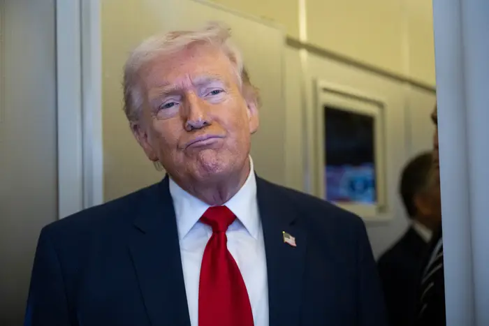 En person i dress og slips står med et nøytralt uttrykk, fanget i et åpenhjertig øyeblikk innendørs