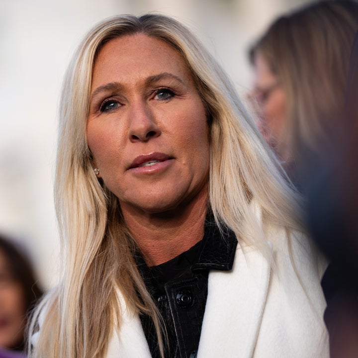 En person med langt blondt hår iført lys frakk og mørk topp, som står utenfor blant en gruppe