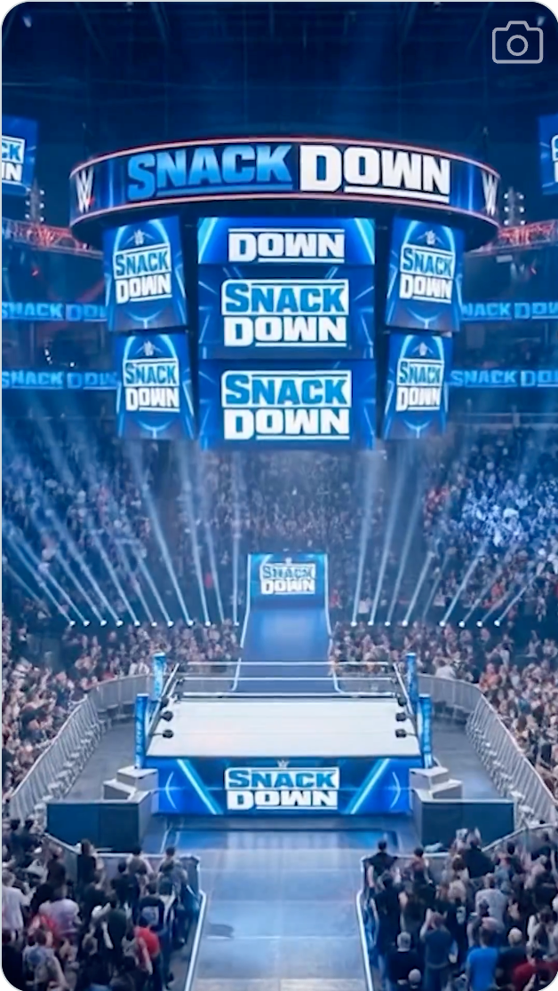 En brytearena med et stort publikum. Skjermene viser "SmackDown," med oppsettet for et WWE-arrangement med en tydelig opplyst ring
