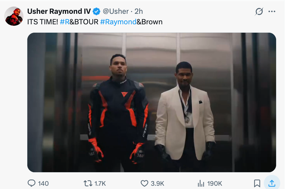 To menn står i en heis. Den venstre har på seg et sporty antrekk, den høyre har på seg en hvit blazer og svarte bukser