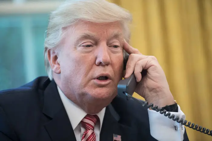 En person i dress snakker i telefonen mens han sitter