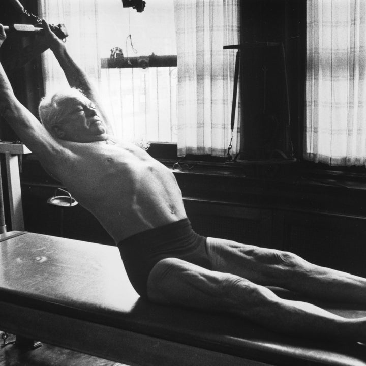 En eldre mann som trener på en Pilates-reformator i et treningsstudio, og demonstrerer fleksibilitet og styrke