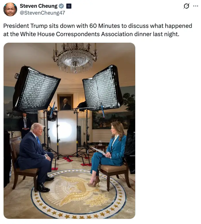 To personer sitter i et formelt intervjuoppsett, under skarpe studiolys, i et rom med presidentinnredning