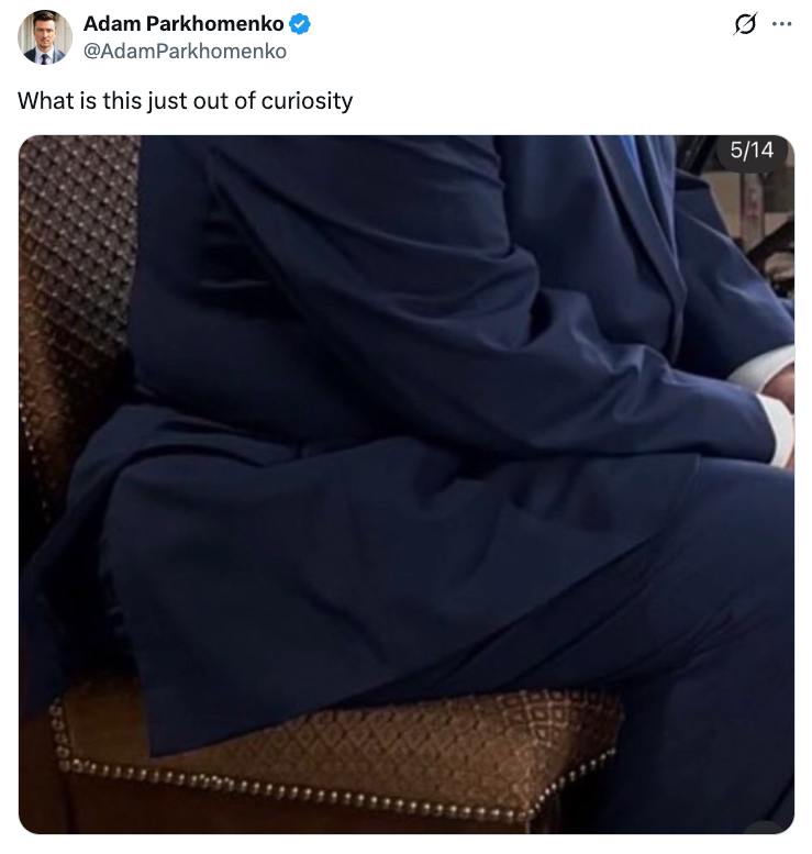 Person i blå dress sitter, delvis synlig, på en mønstret stol
