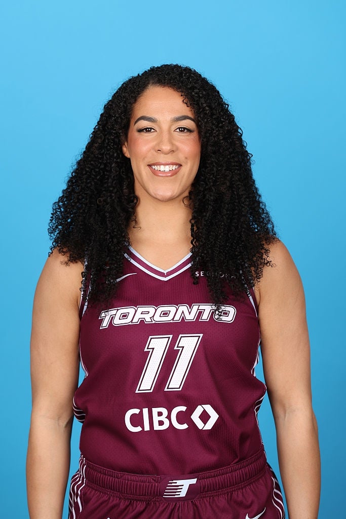 Person med krøllete hår iført en Toronto basketballtrøye nummer 11, smilende
