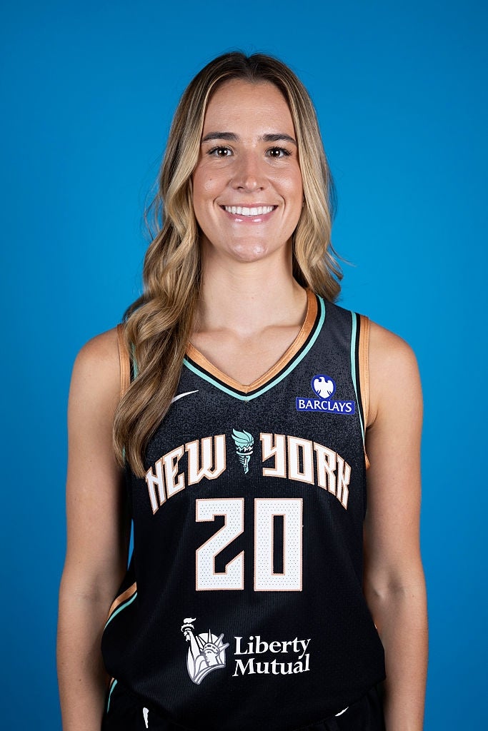 En person i en basketballtrøye fra New York med tallet 20 smiler til kameraet