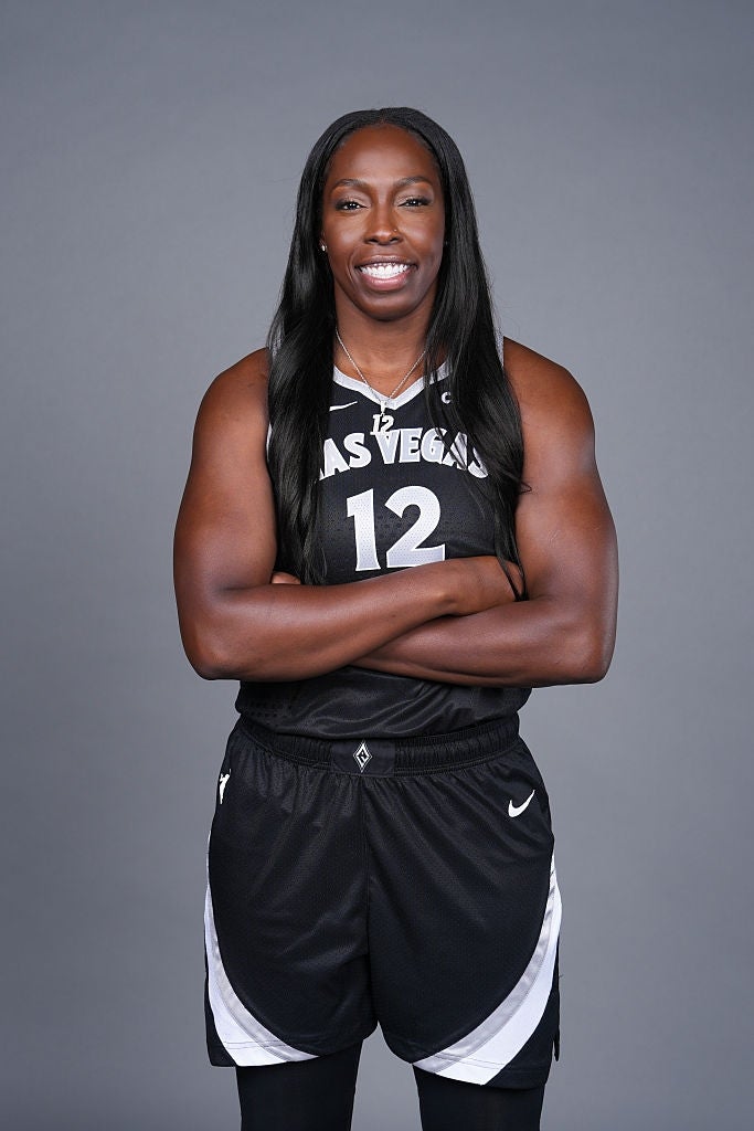 Basketballspiller i Las Vegas-trøye med nummer 12, stående armene i kors, smilende