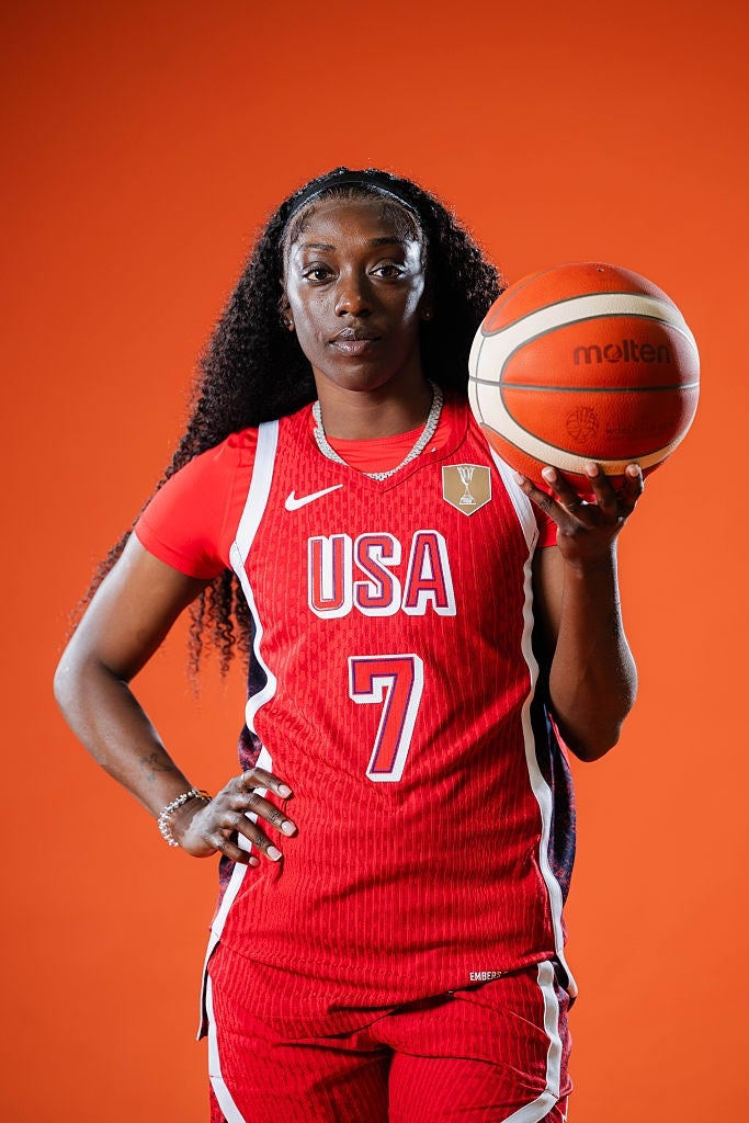 Basketballspiller i en USA-trøye som holder en basketball, poserer selvsikkert