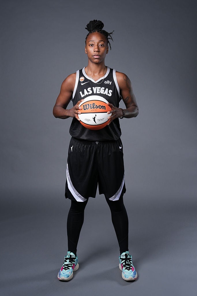 Basketballspiller i Las Vegas-trøye holder en ball, stående i studio